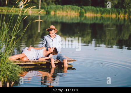 girlfriend lying on boyfriend's lap by lake at park Stock Photo