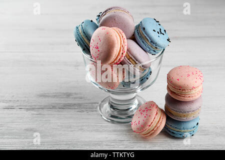 Tasty macaroons in glass dish on wooden table Stock Photo