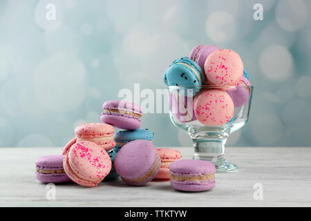 Tasty macaroons in glass dish on wooden table Stock Photo