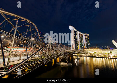 Helix Bridge over Singapore River by Marina Bay Sands against sky at night Stock Photo