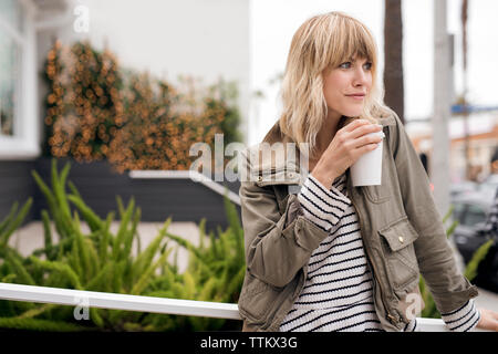 Thoughtful young woman drinking coffee outdoors Stock Photo