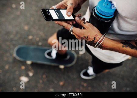 Low section of man using mobile phone while standing on street Stock Photo