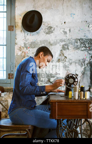 Side view of female fashion designer using sewing machine in workshop Stock Photo