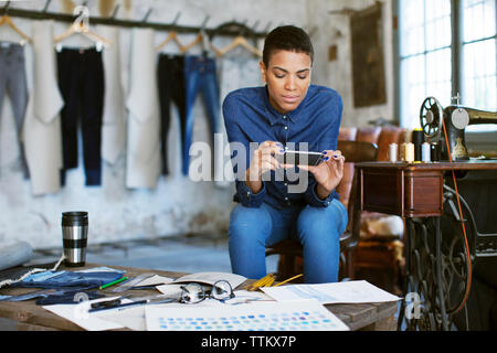 Confident fashion designer using phone while working at workshop Stock Photo