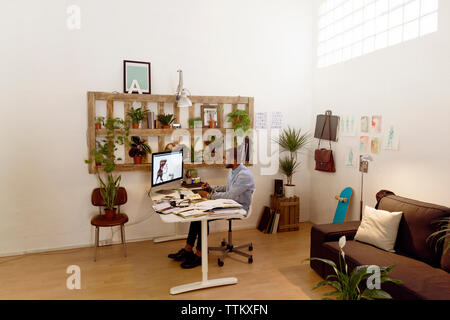 Male illustrator making painting on computer in creative office Stock Photo