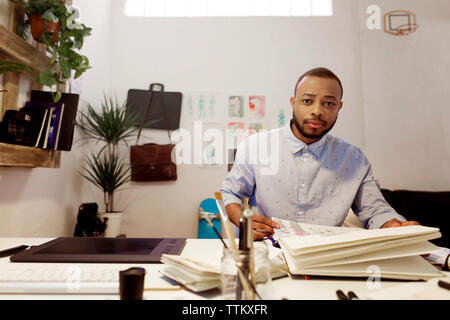 Portrait of confident illustrator sitting at desk in creative office Stock Photo