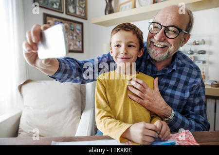 Happy senior man taking selfie with grandson at home Stock Photo