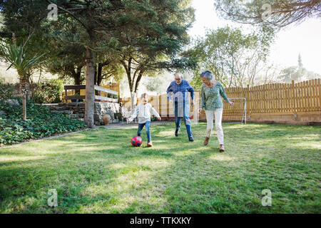 Grandparents playing soccer with grandson at yard Stock Photo