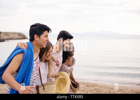 Cheerful friends walking on beach during vacation Stock Photo