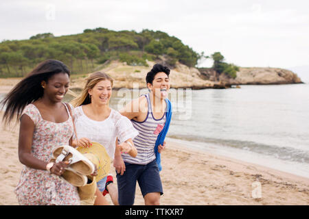 Cheerful friends running on beach during vacation Stock Photo