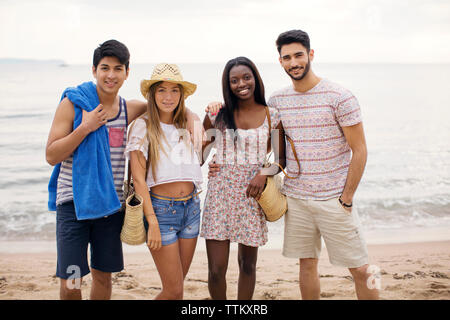 Portrait of happy multi-ethnic friends standing on beach Stock Photo