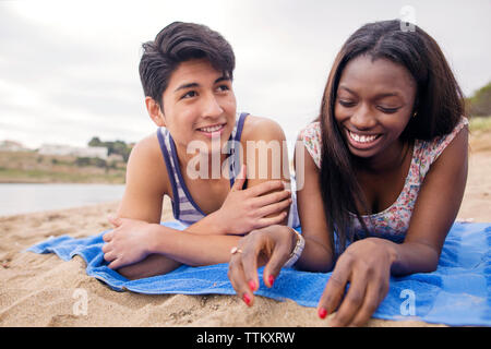 Happy multi-ethnic couple lying on blanket at beach Stock Photo