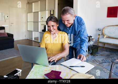 Happy senior couple using laptop while planning vacation at home Stock Photo