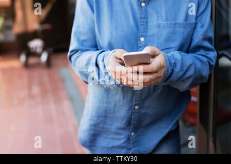 Midsection of senior man using smart phone at porch Stock Photo