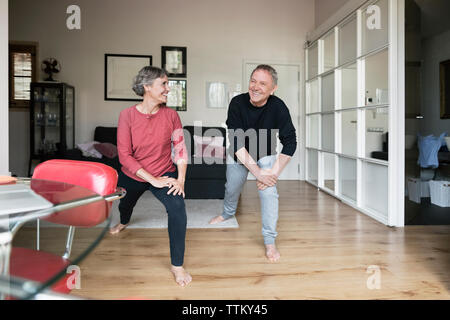 Happy senior couple doing stretching exercise at home Stock Photo