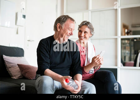 Happy senior couple using smart phone in living room Stock Photo