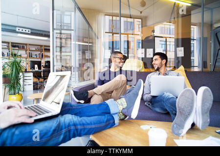 Low section of businessman using laptop computer while coworkers smiling in office Stock Photo