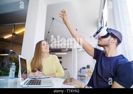 Colleagues examining virtual reality simulator in office Stock Photo