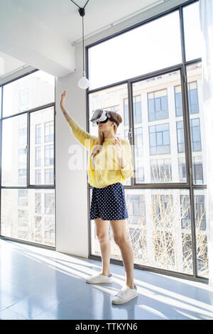 businesswoman using virtual reality simulator while standing by window in office Stock Photo