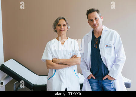 Portrait of confident doctors standing against wall at hospital Stock Photo
