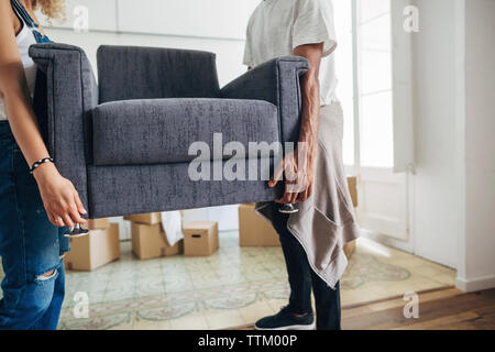 Couple carrying armchair while standing at new house Stock Photo
