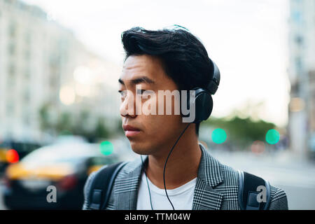 businessman looking away while listening music in city Stock Photo