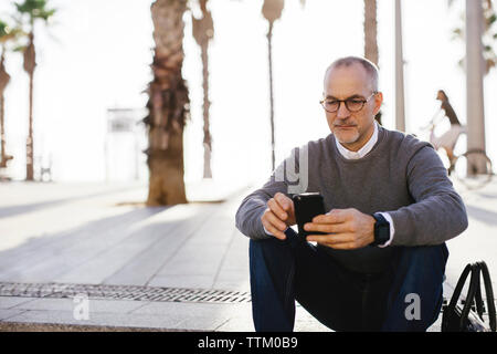 Serious businessman using smart phone in city Stock Photo