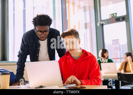 Friends discussing over laptop computers in library Stock Photo