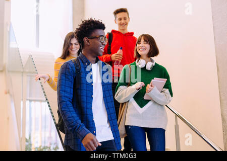Low angle view of friends talking while moving down on steps at library Stock Photo