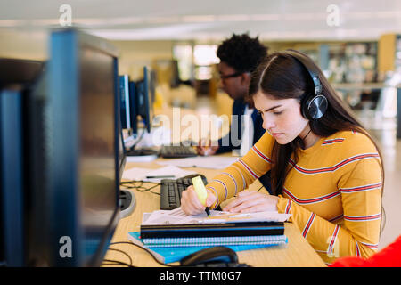 Students using desktop computers while sitting in library Stock Photo