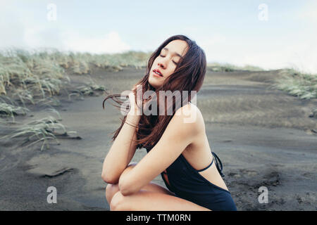 Close-up of beautiful woman crouching on wet beach Stock Photo