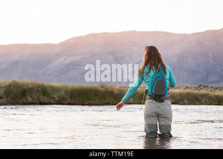 Young woman fly-fishing while standing in Owens River against mountains  Stock Photo - Alamy