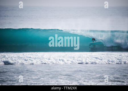 Person surfing in rolling surf at Mentawai Islands Stock Photo