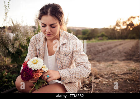 Female farmer holding beautiful flowers on field Stock Photo