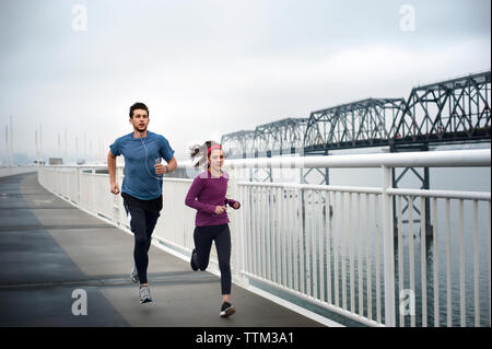 Determined male and female athletes running on Bay Bridge Stock Photo