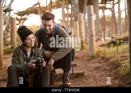 Hiking couple watching photographs on camera at forest Stock Photo