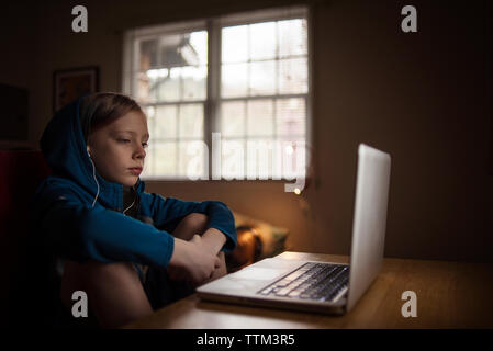 Boy using laptop computer on table while sitting at home Stock Photo
