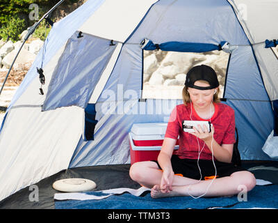 Boy using smart phone while sitting in tent Stock Photo