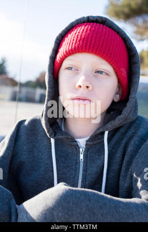 Thoughtful boy wearing knit hat and hooded shirt while looking away Stock Photo