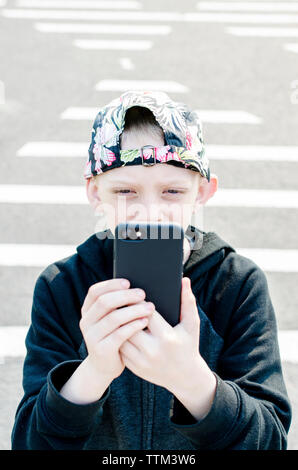 High angle view of boy using mobile phone while standing on road Stock Photo