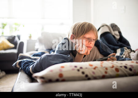 Boy using mobile phone while lying on bed at home Stock Photo