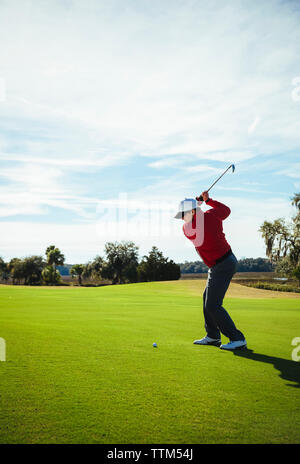 Full length of man playing golf while standing on field against blue sky Stock Photo