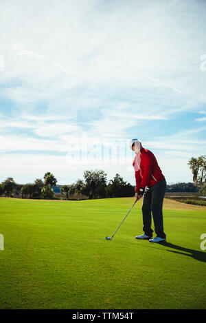 Full length of man playing golf while standing on field against sky Stock Photo