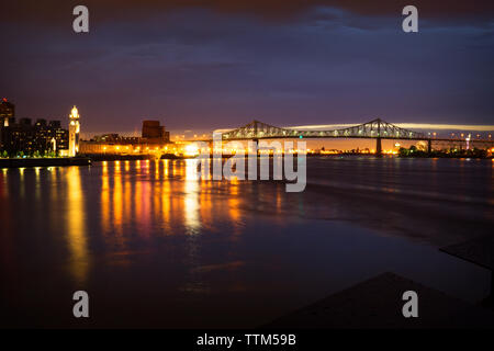 Illuminated bridge over river at night Stock Photo