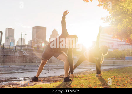 Couple practicing yoga in park during sunrise Stock Photo