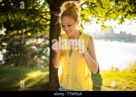 Beautiful blonde girl blowing bubbles and having fun in park Stock Photo