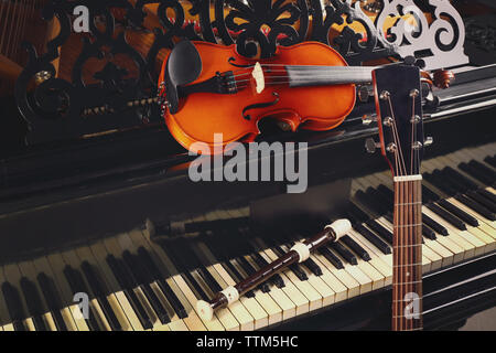 Flute, violin and guitar neck on piano Stock Photo