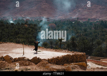 High angle view of man wearing traditional clothing while skateboarding against palm trees Stock Photo