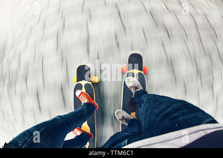 Low section of couple skateboarding on road Stock Photo