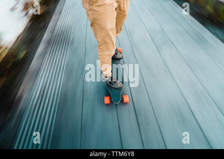 Low section of man skateboarding on wooden floorboard in city Stock Photo